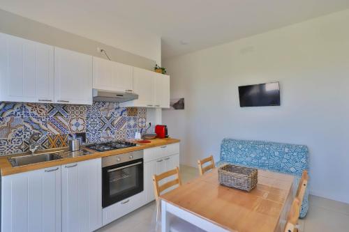 a kitchen with white cabinets and a wooden table with a tableablish at I giardini dell'Olimpo in Paestum