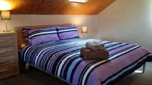 a bedroom with a large bed with purple pillows at Stuarts Cottage in Wanaka