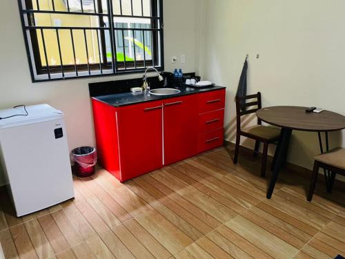 a red kitchen with a sink and a table at Waterland Suites in Paramaribo