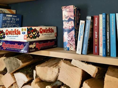 a shelf filled with books and cheese on it at The Mousetrap Inn in Bourton on the Water
