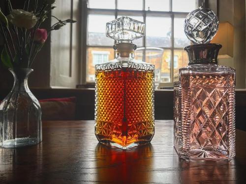 two glass bottles sitting on a wooden table at The Mousetrap Inn in Bourton on the Water