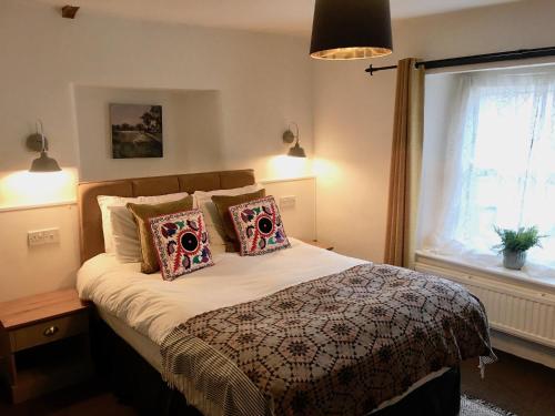 a bedroom with a bed with pillows and a window at The Mousetrap Inn in Bourton on the Water