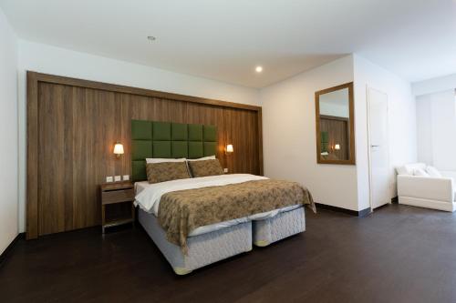 Schlafzimmer mit einem großen Bett mit einem grünen Kopfteil in der Unterkunft Hotel Cataleya in Almere