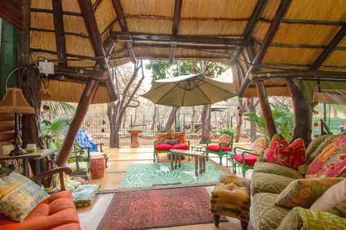 a living room with couches and an umbrella at Wielewaal Bush Lodge in Marloth Park