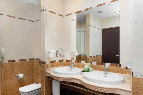 a bathroom with two sinks and a toilet and a mirror at Pirin Park Hotel in Sandanski