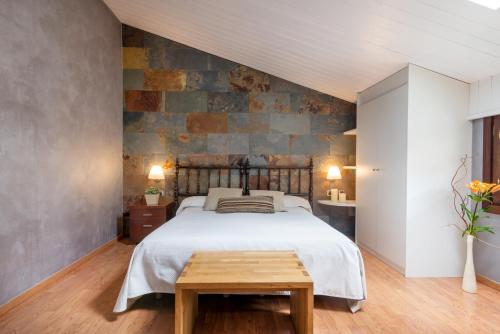 a bedroom with a bed and a stone wall at Hotel Els Caçadors de Ribes in Ribes de Freser