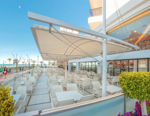Una fila de mesas y sillas blancas en un edificio. en Hotel RH Corona del Mar 4* Sup, en Benidorm