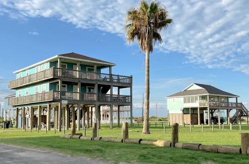 a building with a palm tree next to a house at Abby Sands Castle Home in Caplen