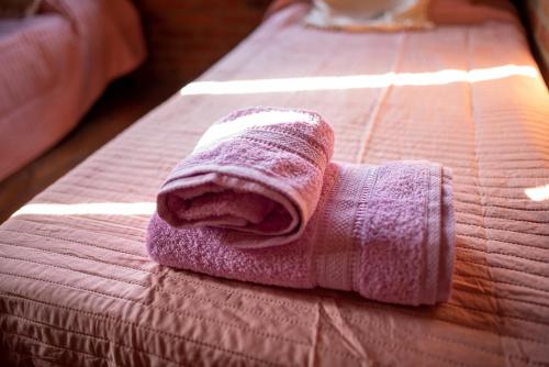 een roze handdoek ligt op een bed bij Cabañas Agua de Río in Santa Rosa de Calamuchita