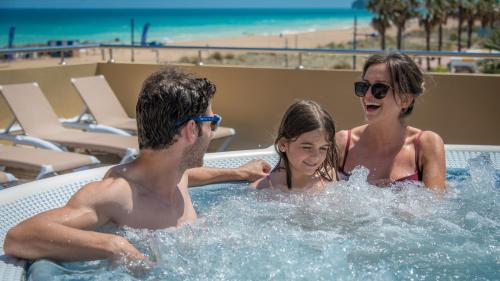 a man and a woman and a little girl in a hot tub at Hotel RH Casablanca Suites in Peniscola