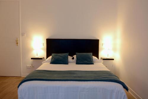 a bedroom with a large bed with two lamps at Hotel Joly in Armentières