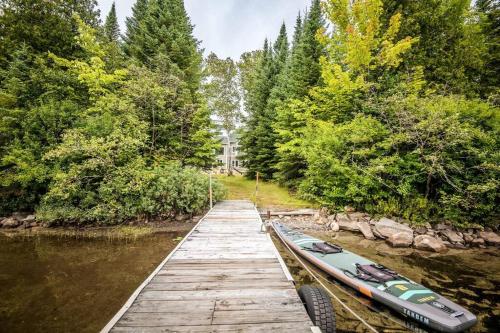a wooden dock with two canoes on a river at Le Chaleureux du Lac Blanc - Nominingue in Nominingue