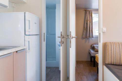 a kitchen with a refrigerator and a door to a room at Camping Daino in Pietramurata