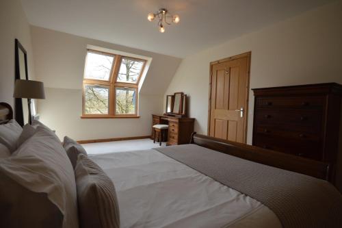 ein Schlafzimmer mit einem Bett, einer Kommode und einem Fenster in der Unterkunft Tall Pines Apartment in Spean Bridge