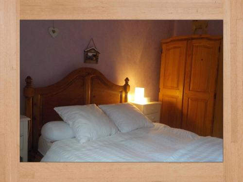 a bedroom with a white bed with a wooden headboard at LES LILAS in Sainte-Marie-aux-Mines