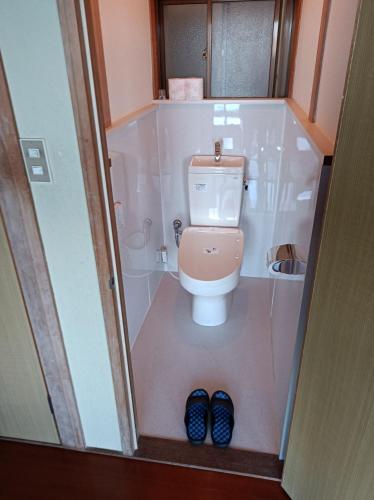 a bathroom with a toilet and a pair of blue shoes at Minshuku Kamagari in Kure