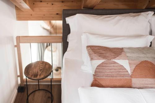 a bed with white pillows and a stool next to it at apartments55 in Bressanone