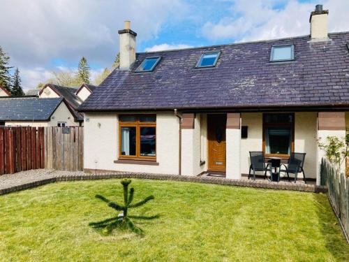 a house with a lawn in front of it at Aonachan Cottage in Spean Bridge
