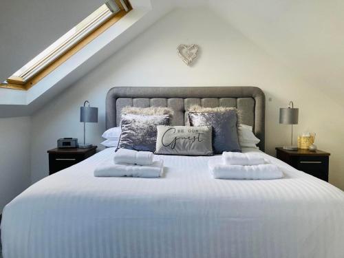 a bedroom with a large white bed with pillows at Aonachan Cottage in Spean Bridge