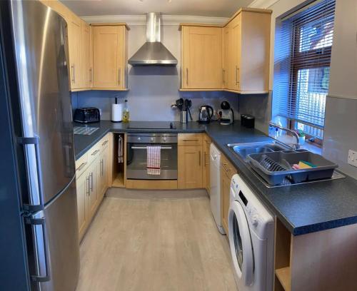 uma cozinha com armários de madeira e um frigorífico de aço inoxidável em Aonachan Cottage em Spean Bridge