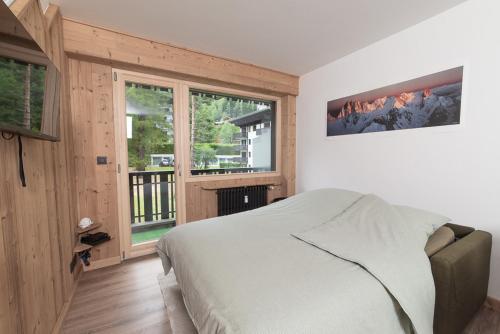 - une chambre avec un lit et une grande fenêtre dans l'établissement Charmant Studio tout confort au Brévent-Chamonix, à Chamonix-Mont-Blanc