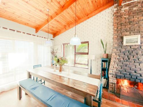 une salle à manger avec une table en bois et un mur en briques dans l'établissement La Mer Seafront Selfcatering Accommodation Kleinmond, à Kleinmond