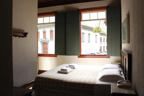 een slaapkamer met een bed met handdoeken erop bij Hotel Quadrado in Santa Bárbara