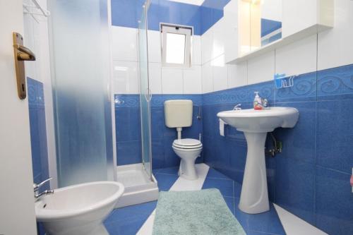 a blue and white bathroom with a sink and a toilet at Apartments and rooms with a swimming pool Babici, Umag - 3046 in Umag