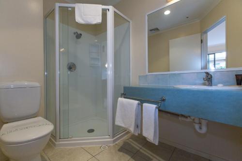 a bathroom with a shower and a toilet and a sink at Fernhill Motor Lodge in Lower Hutt