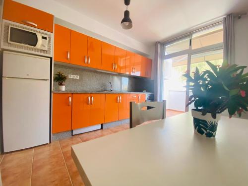 VV Estrella في بويرتو دي موغان: مطبخ مع دواليب برتقاليه وثلاجة بيضاء