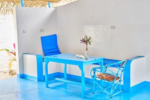 ein blauer Tisch und ein Stuhl mit einer Vase drauf in der Unterkunft Beach House Paje in Paje
