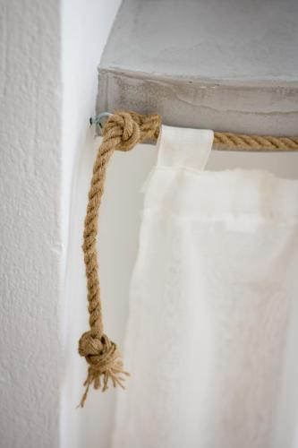 a rope attached to a white curtain on a wall at Eris Studios in Adamas