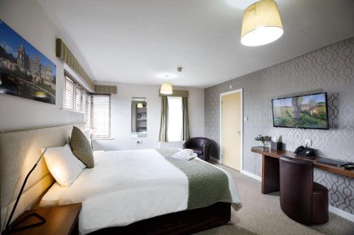 a hotel room with a large bed and a television at Abbeyfield Lodge in Stockton-on-Tees