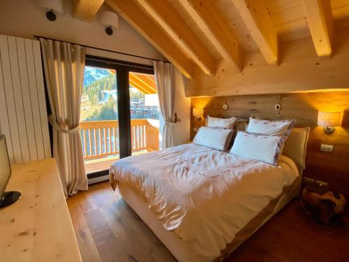 een slaapkamer met een bed en een groot raam bij Chalet Ronchi - Foppolo Ski in Foppolo