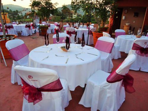 un groupe de tables et de chaises avec des archets blancs et rouges dans l'établissement Hotel Zihua Caracol, à Zihuatanejo