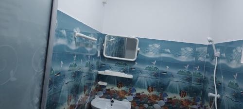 a bathroom with a painting on the wall at Nilaveli Beach Rooms in Nilaveli