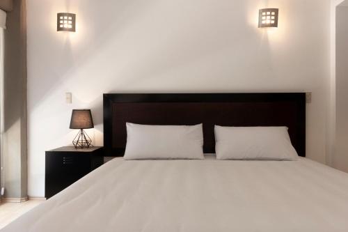 a bedroom with a large white bed with two pillows at Prosperidad by HomiRent in Mexico City