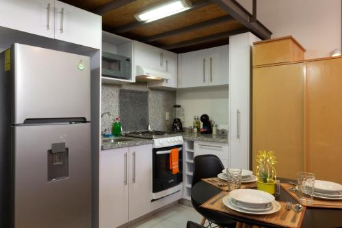 a kitchen with white cabinets and a table and a refrigerator at Prosperidad by HomiRent in Mexico City