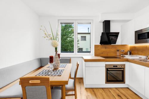a kitchen with white cabinets and a table with chairs at Wienerberg-Apartments in Vienna