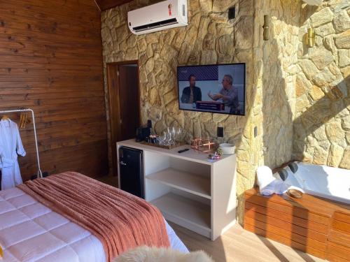 a bedroom with a bed and a tv on a stone wall at Recanto Entre Rios in Bom Jardim da Serra