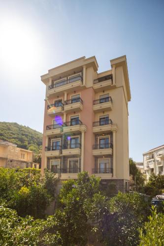 a tall pink building with trees in front of it at Hotel Vladimir in Budva