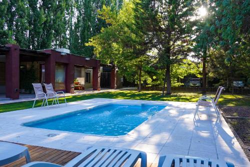 a swimming pool with chairs next to a house at Cabañas Parque Vistalba in Ciudad Lujan de Cuyo