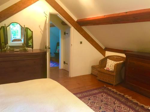 a bedroom with a bed and a mirror and a chair at St Michaels Coach House in Crediton