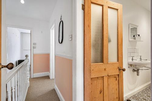 a bathroom with a sink and a wooden door at Finest Retreats - Poppy Cottage of Penzance in Penzance