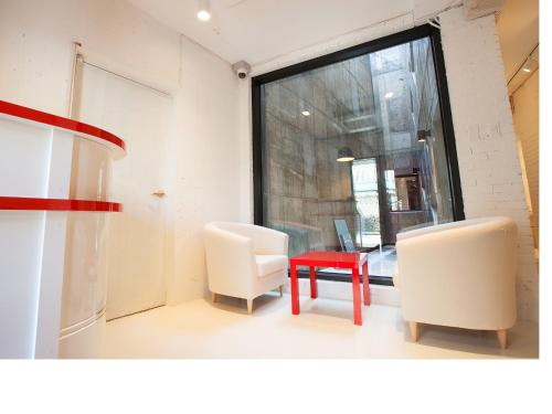 a room with two chairs and a red table at Mir Guesthouse in Jeju