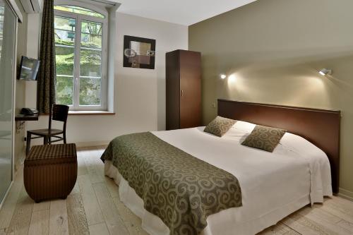 a bedroom with a large bed and a chair at Le Coligny in Brantôme