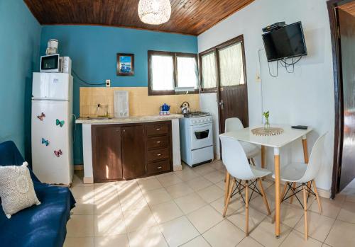 a kitchen with a white refrigerator and a table with chairs at Cabañas Virazon Aguas Dulces in Aguas Dulces