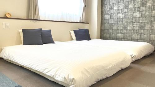 a large white bed with blue pillows in a room at Global Resort ONO de LUNE in Hatsukaichi