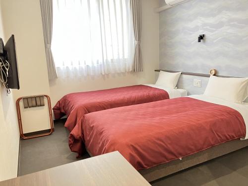 a hotel room with two beds with red sheets at Global Resort ONO de LUNE in Hatsukaichi