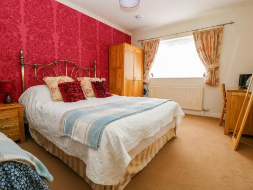 a bedroom with a large bed with red wallpaper at Dutch Blues in Malton